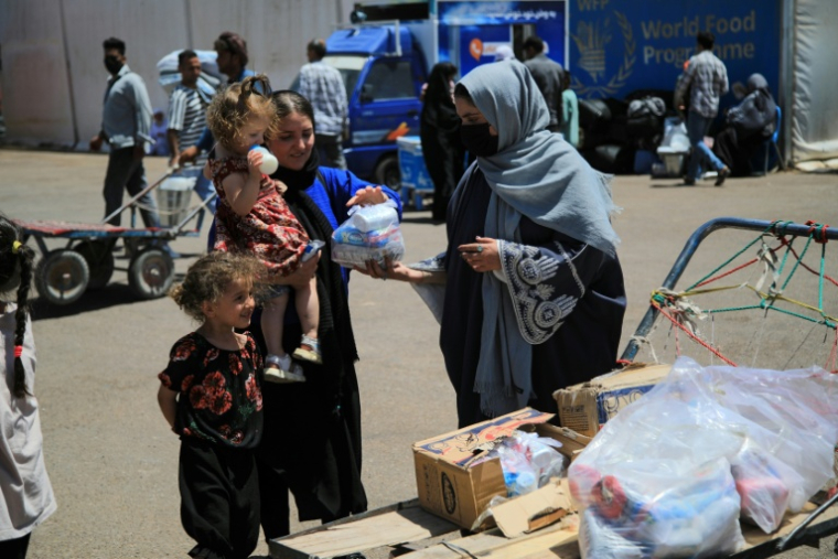 Fatima Rezaei (d), une bénévole afghane distribuant des produits d'hygiène à des compatriotes expulsés d'Iran, au poste frontière d'Islam Qala, dans la province de Hérat en Afghanistan, le 24 juillet 2025 ( AFP / Mohsen KARIMI )