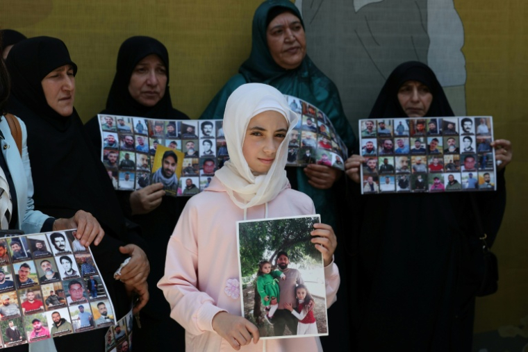 Des membres de familles de détenus dans les prisons israéliennes montrent les photos de leurs proches le 12 août 2026 à Beyrouth lors d'une manifestation devant le siège de la Croix-Rouge ( AFP / Anwar AMRO )