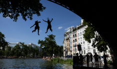 Des jeunes sautent d'un pont dans le canal Saint-Martin lors d'une vague de chaleur à Paris, le 22 juin 2026 ( AFP / JOEL SAGET )