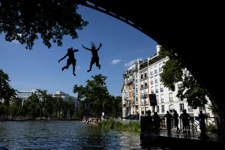 Des jeunes sautent d'un pont dans le canal Saint-Martin lors d'une vague de chaleur à Paris, le 22 juin 2026 ( AFP / JOEL SAGET )