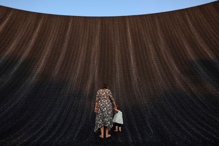 Une femme tient la main d'un bébé alors qu'ils profitent tous deux de la cascade de l'Expo à la COP28, à Dubaï