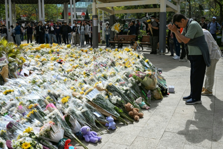 Des personnes déposent des fleurs devant les immeubles d'appartements du complexe résidentiel Wang Fuk Court après l'incendie meurtrier du 26 novembre, le 1er décembre 2025 à Hong Kong ( AFP / Peter PARKS )