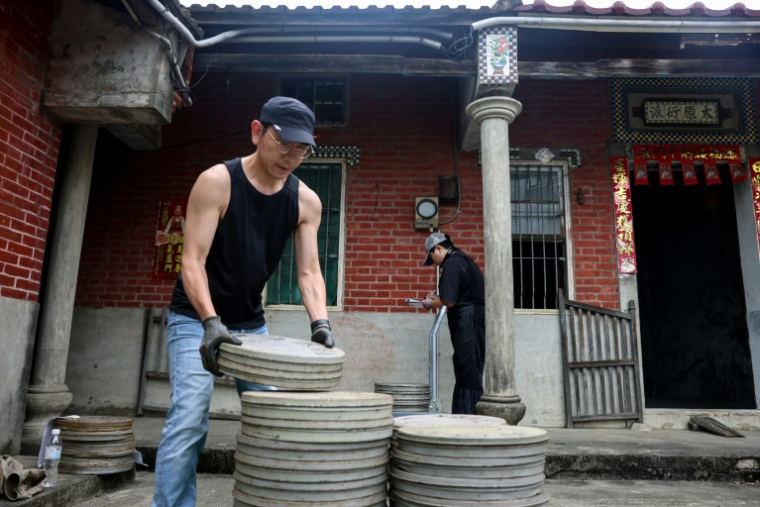 Un employé de l'Institut taïwanais du cinéma et de l'audiovisuel (TFAI) empile des bobines de vieux films taïwanais à restaurer issus d'une collection privée, le 29 mai 2026 à Changhua, dans la province de Taïwan ( AFP / I-Hwa Cheng )