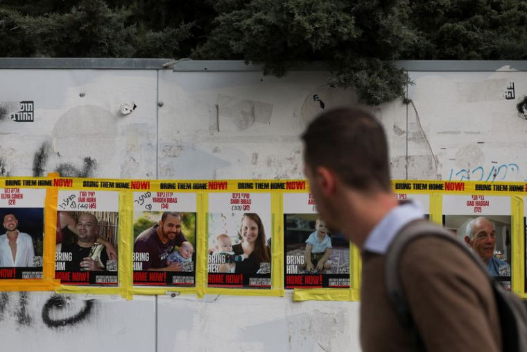 Un homme passe devant des photos de la famille Bibas, à Jérusalem