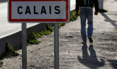 Un migrant passe devant un panneau à Calais