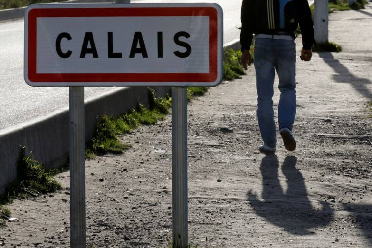 Un migrant passe devant un panneau à Calais