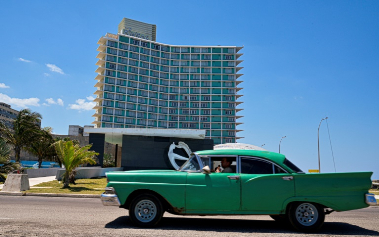 Un berline américaine passe devant l'hôtel Riviera qui a abrité un casino jusqu'à la révolution castriste de 1959, à La Havane, le 14 avril 2025 ( AFP / ADALBERTO ROQUE )