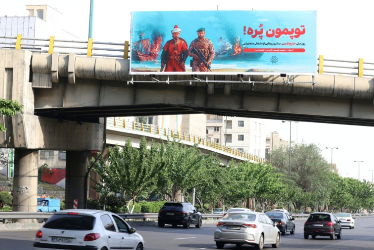 Une affiche anti-américaine sur laquelle est écrit en persan "Nos canons sont pleins" en référence au détroit d'Ormuz, déployée sur un pont au-dessus d'une autoroute à Téhéran, le 12 mai 2026 ( AFP / ATTA KENARE )