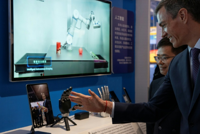 Le Premier ministre espagnol Pedro Sanchez observe une main robotisée lors d'une visite à l'Université de l'Académie chinoise des sciences à Pékin, le 13 avril 2026 ( POOL / ANDRES MARTINEZ CASARES )