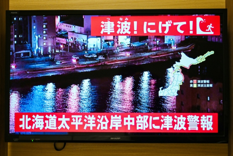 Un avertissement indiquant "Tsunami ! Courez !" (en haut) et "Alerte au tsunami émise pour la côte Pacifique du centre de Hokkaido" s'affiche sur un écran de télévision à Sapporo, au Japon, le 9 décembre 2025 ( AFP / GREG BAKER )