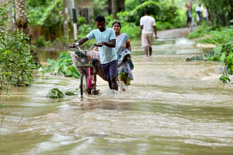 Des villageois dans une rue inondée après de fortes pluies à Kampur, dans l'Etat d'Assam, au nord-est de l'Inde, le 1er juin 2025 ( AFP / Biju BORO )