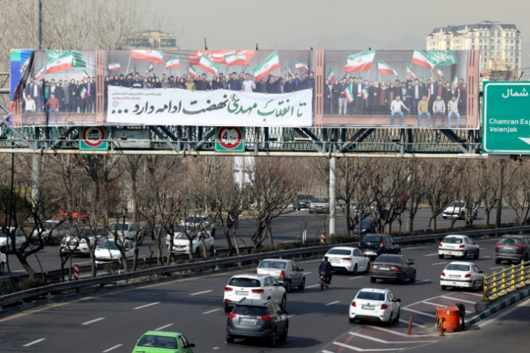 La passerelle piétonne d'une autoroute sur laquelle est déployée une immense banderole montrant des personnes agitant le drapeau iranien, à Téhéran, le 18 février 2026 ( AFP / ATTA KENARE )