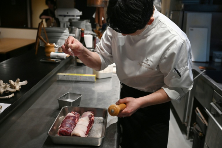 Le chef Kiyoshi Fujimoto cuisine de la viande d'ours dans son restaurant de Sapporo, dans la région d'Hokkaido, au Japon, le 9 décembre 2025 ( AFP / GREG BAKER )