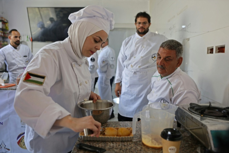 Des jeunes Palestiniens apprennent les bases de la cuisine à la Smile Kitchen Academy, dans le quartier de Rimal à Gaza, le 24 juin 2026 ( AFP / Omar AL-QATTAA )