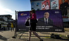 Une femme marche devant les panneaux de publicité électorale de candidats aux élections légisatives au Suriname, à Paramaribo le 23 mai 2025 ( AFP / Juan BARRETO )