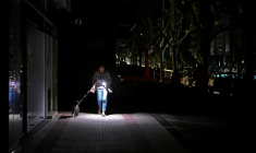 Un passante promène son chien en s'éclairant avec son téléphone, le 28 avril 2025 à Vigo, dans le nord-ouest de l'Espagne, pendant une panne d'électricité géante ( AFP / MIGUEL RIOPA )