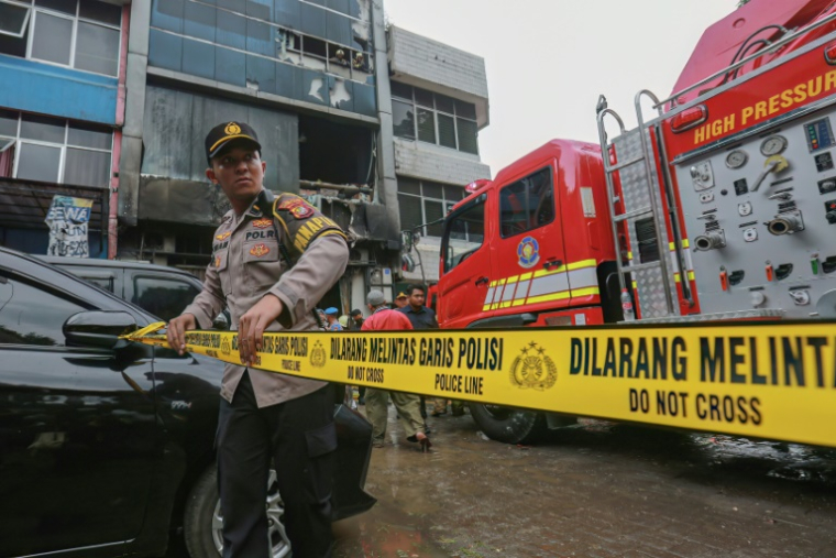 Un membre de la police indonésienne barre l'accès à l'immeuble qui a pris feu à Jakarta le 9 décembre 2025 ( AFP / SYNATRIA RESPATI )