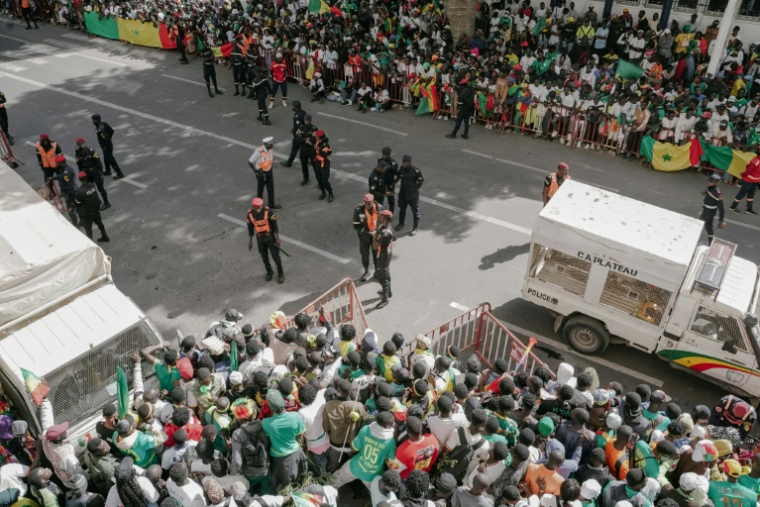 Des supporters de l'équipe de football sénégalaise sont postés le 20 janvier 2026 le long de l'itinéraire du passage d'une grande parade des Lions de la Teranga, célébrant leur victoire lors de la finale de la CAN-2025 face au Maroc ( AFP / Carmen Abd Ali )