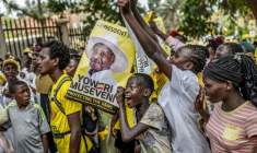 De jeunes partisans du président ougandais sortant Yoweri Museveni brandissent des affiches électorales et chantent des slogans à son dernier meeting de campagne, le 13 janvier 2026 à Kampala ( AFP / - )