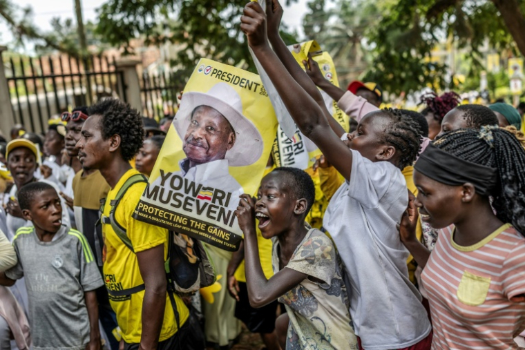 De jeunes partisans du président ougandais sortant Yoweri Museveni brandissent des affiches électorales et chantent des slogans à son dernier meeting de campagne, le 13 janvier 2026 à Kampala ( AFP / - )