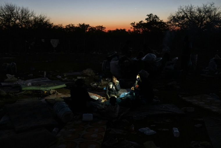 Une famille dans l'attente de son rapatriement prend un repas dans le camp de transit de Musina, en Afrique du Sud, le 8 juillet 2026 ( AFP / EMMANUEL CROSET )