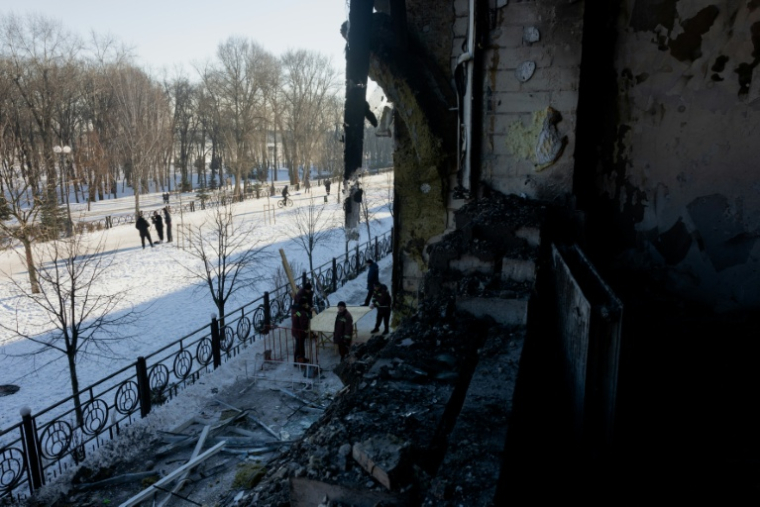 Des personnes apportent des planches pour boucher des fenêtres détruites après l'attaque par des drones d'une clinique privée à Kiev, le 5 janvier 2026, en Ukraine ( AFP / Tetiana DZHAFAROVA )