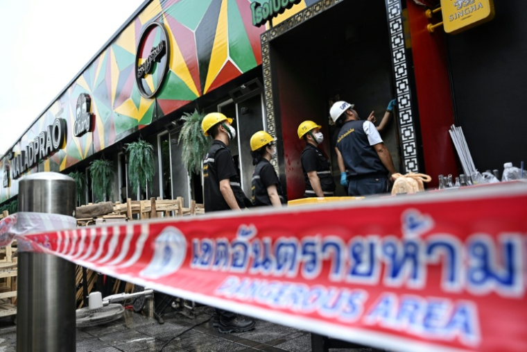 Des membres de la police scientifique inspectent les décombres calciné du bar-restaurant Rong Beer Na Lat Phrao, le 13 juillet 2026 à Bangkok, en Thaïlande ( AFP / Lillian SUWANRUMPHA )