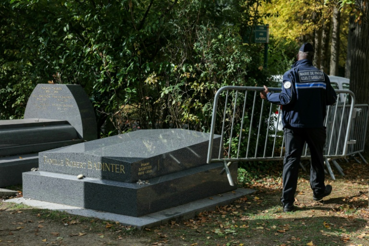Un policier enlève le 9 octobre 2025 au cimetière de Bagneux, près de Paris, les barrières qui protégeaient la tombe de Robert Badinter, nettoyée après avoir été profanée à quelques heures de son entrée au Panthéon ( AFP / Thomas SAMSON )