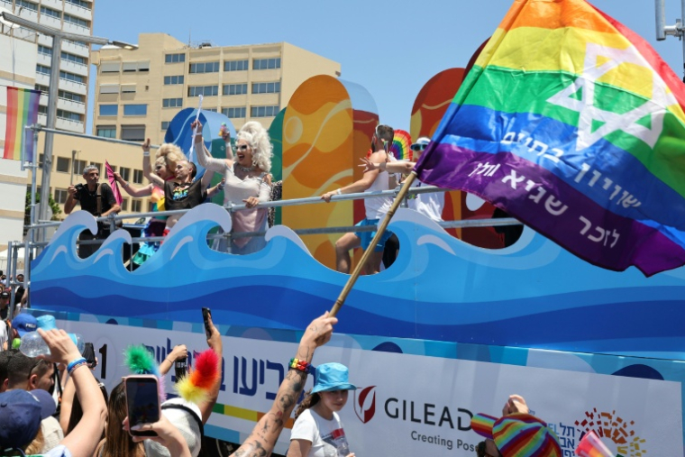 Un participant à la marche des fiertés brandit un drapeau arc-en-ciel avec une étoile de David, à Tel-Aviv le 12 juin 2026 ( AFP / Jack GUEZ )