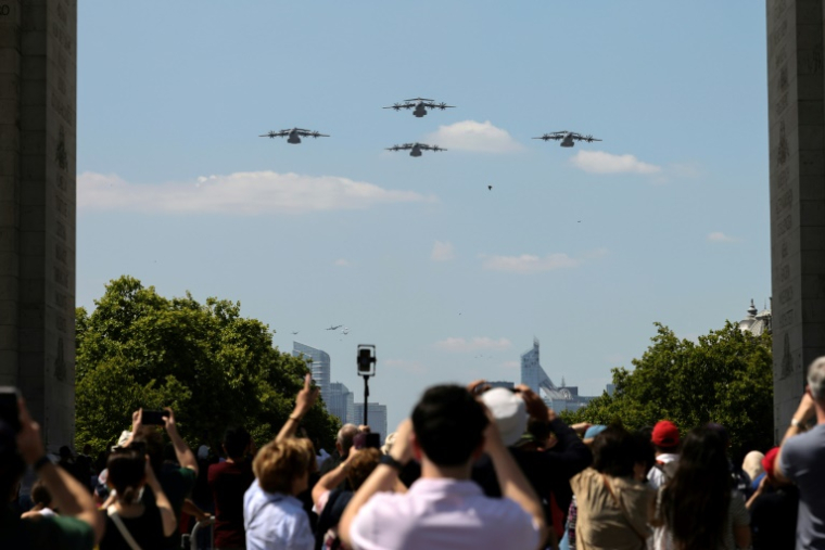 Des passants prennent des photos d'Airbus A400M de l'Armée de l'air française survolant l'Arc de Triomphe, le 9 juillet 2025 à Paris, lors d'une répétition du défilé annuel du 14 juillet ( AFP / ALAIN JOCARD )