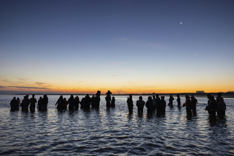 Des migrants avancent dans l'eau pour essayer de monter à bord d'un "bateau-taxi" pour traverser la Manche le 19 septembre 2025 au large de la plage de Gravelines, dans le nord de la France ( AFP / Sameer Al-DOUMY )