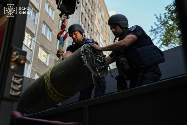 Photo, prise et diffusée par le Service d'État pour les situations d'urgence, le 28 juin 2026, de démineurs chargeant un fragment de missile russe sur un camion après une attaque aérienne à proximité d'immeubles résidentiels à Kiev, en Ukraine ( Service d'État pour les situations d'urgence de l'Ukraine / - )
