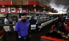 Un serveur portant un masque de protection passe devant des clients qui mangent chez Pann's, un café classique des années 1950, à Los Angeles