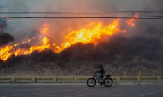 Une personne fait du vélo alors que l'incendie de Palisades brûle pendant une tempête de vent sur la côte ouest de Los Angeles