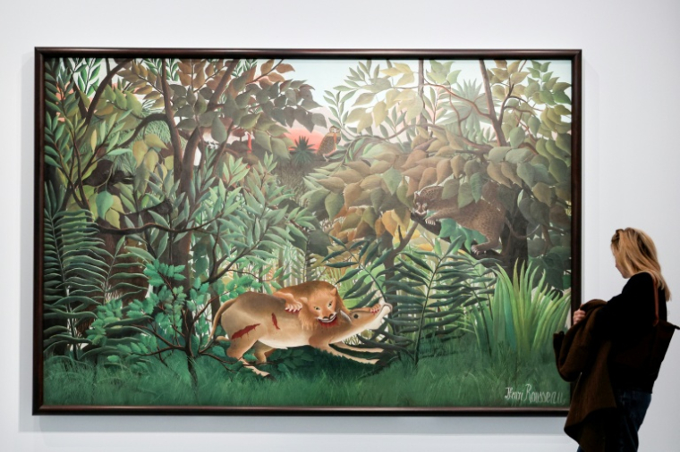 Une visiteuse regarde le tableau "Le lion ayant faim se jette sur l'antilope" de Henri Rousseau, lors d'une exposition consacrée au peintre au musée de l'Orangerie à Paris, le 20 mars 2026 ( AFP / ALAIN JOCARD )