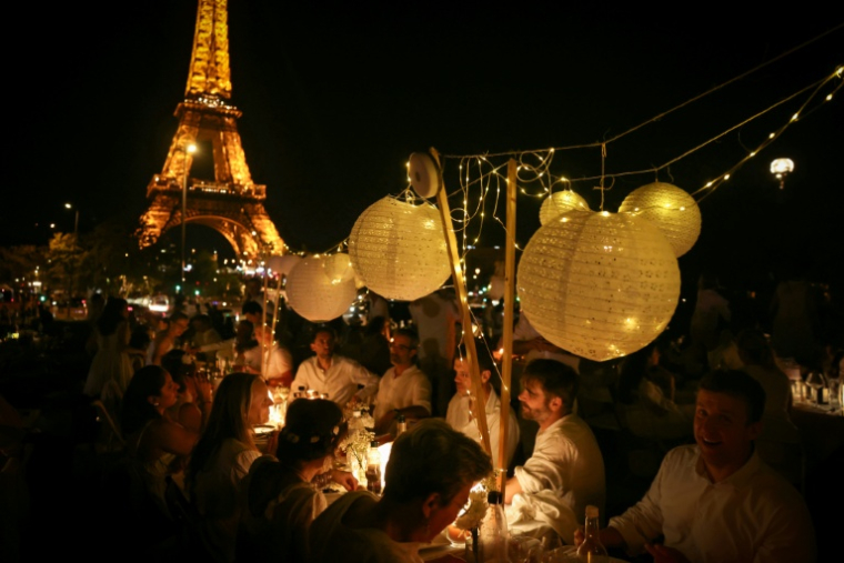 Des centaines de convives habillés en blanc se rassemblent au Trocadéro, face à la Tour Eiffel, pour un dîner géant secret de dernière minute dans le centre de Paris, le 18 juin 2026 ( AFP / Alain JOCARD )