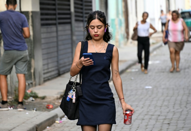 Une femme utilise son téléphone portable dans une rue de La Havane, le 3 juin 2025. ( AFP / YAMIL LAGE )