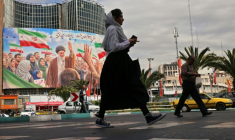 Des passants devant une affiche géante du défunt ayatollah Khamenei, sur la place Valiasr de Téhéran, le 19 avril 2026 ( AFP / ATTA KENARE )