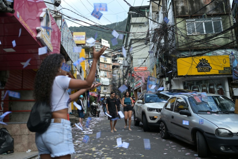 Une femme lance des tracts électoraux à Rocinha, la plus grande favela de Rio de Janeiro, le 4 octobre 2026 ( AFP / Tercio TEIXEIRA )