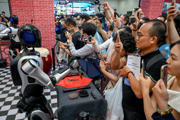 Des robots exécutent différentes tâches devant des visiteurs lors de la World AI Conference (WAIC), le 26 juillet 2025 à Shanghai    ( AFP / - )