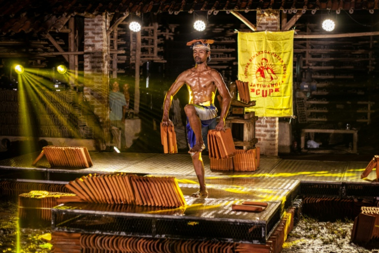 Un ouvrier particile à un concours de culturisme pour défendre la production de tuiles dans la ville indonésienne de Jatiwangi le 11 août 2025  ( AFP / Aditya Irawan )