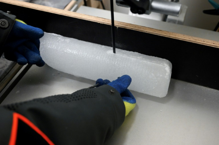 Un scientifique découpe une carotte glaciaire antarctique dans un laboratoire à Bruxelles, le 15 juillet 2025 en Belgique ( AFP / Nicolas TUCAT )