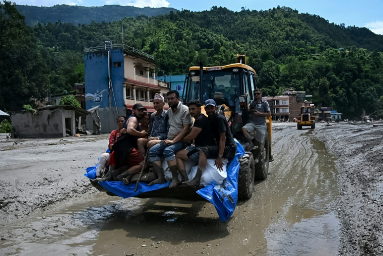 Des sauveteurs transportent des habitants bloqués à l’aide d’un bulldozer après des crues soudaines dans la région de Devighat, dans le district de Nuwakot au Népal, le 27 août 2026 ( AFP / Prakash MATHEMA )