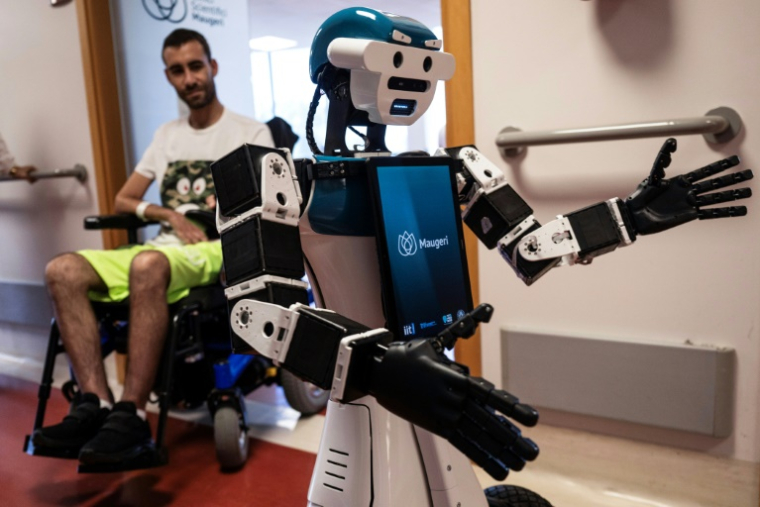 Le robot humanoïde Alter-Ego, conçu par l'Institut italien de technologie, assiste le patient Daniel Senna, à l'hôpital Maugeri de Milan, le 12 juin 2026 ( AFP / MARCO BERTORELLO )