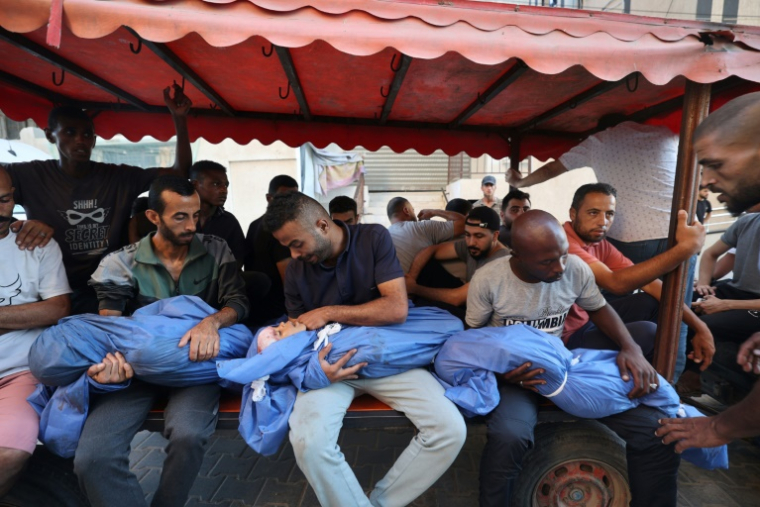 Des hommes portes les corps de trois jeunes palestiniens tués dans une frappe aérienne, le 5 juillet 2025 dans le centre de la bande de Gaza ( AFP / Eyad BABA )