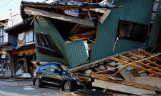 Une voiture endommagée près d'une maison effondrée, suite à un tremblement de terre, à Nanao