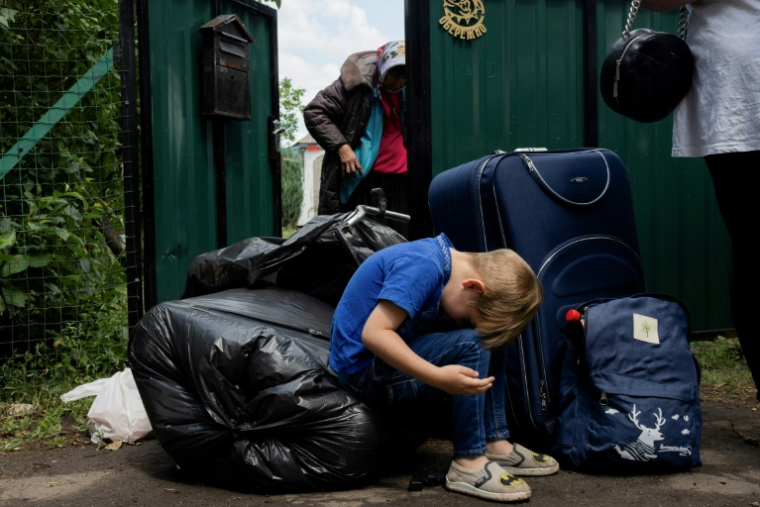 Une famille avec ses affaires attend un bus pour évacuer Mezhova, dans la région de Dnipropetrovsk, à l'est de l'Ukraine, le 17 juin 2025 ( AFP / Tetiana DZHAFAROVA )