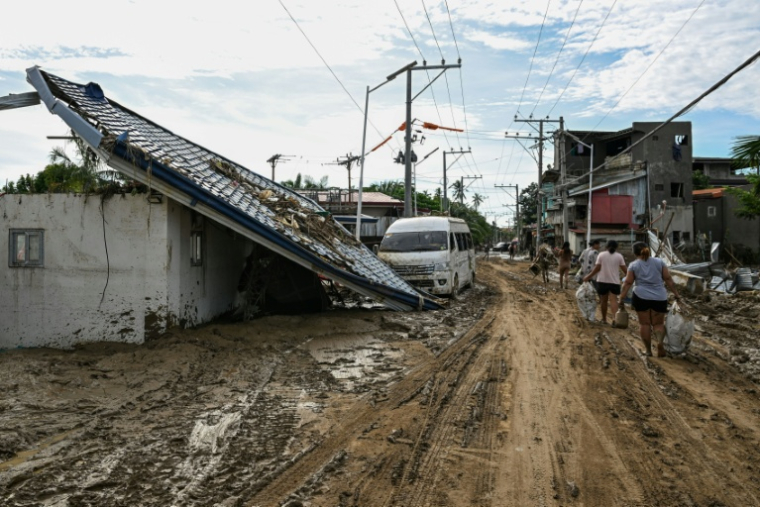 Les habitants marchent le long d'une rue couverte de boue après le passage du typhon Kalmaegi à Liloan, dans la province de Cebu aux Philippines, le 6 novembre 2025 ( AFP / Jam STA ROSA )