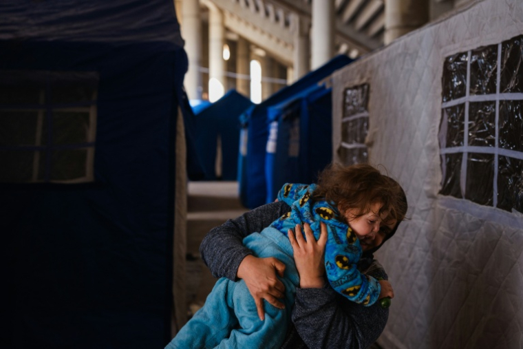 Une femme serre son enfant près de tentes installées dans un stade transformé en centre pour déplacés, à Beyrouth, au Liban, le 27 mars 2026 ( AFP / Dimitar DILKOFF )