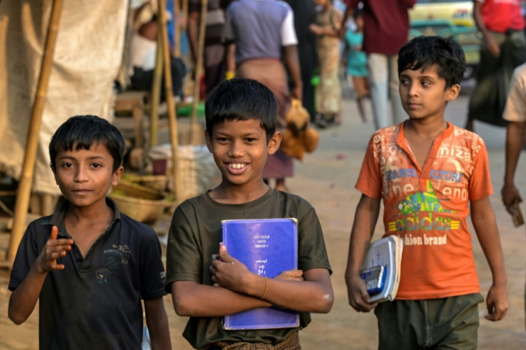 Des enfants réfugiés rohingyas portent leurs manuels scolaires au camp de réfugiés de Kutupalong, le 17 décembre 2025 à Ukhia, au Bangladesh ( AFP / Munir UZ ZAMAN )